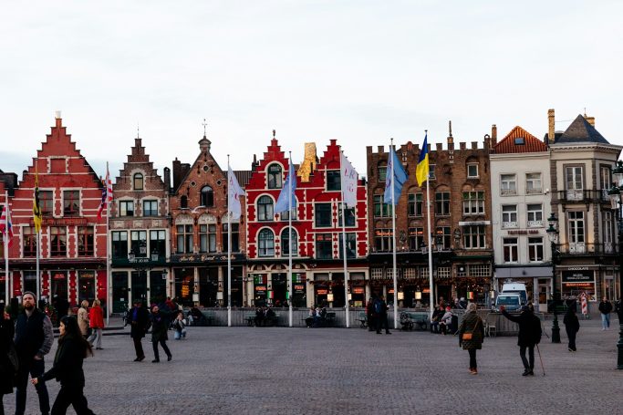 Row of historic buildings with decorative façades in a bustling square.